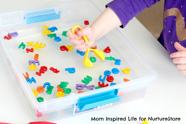 a small sensory bin with rice and scoops on a towel